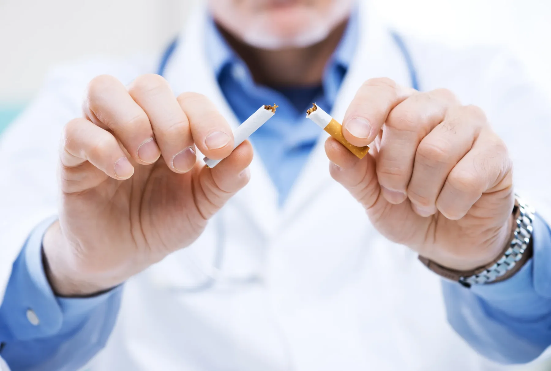 A healthcare professional breaking a cigarette, representing medical advice and support for smoking cessation