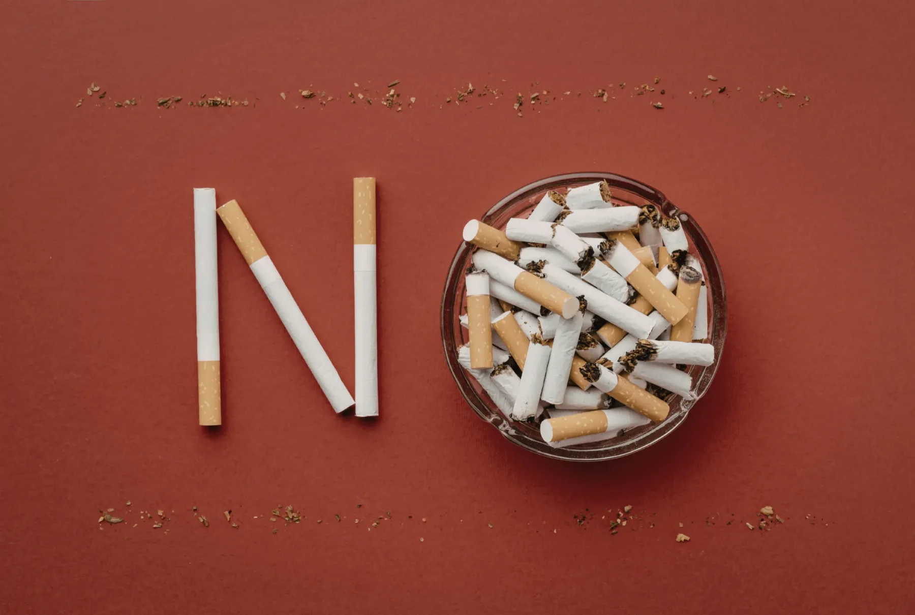Cigarettes arranged beside a full ashtray, representing the habitual cues and routines that surround smoking